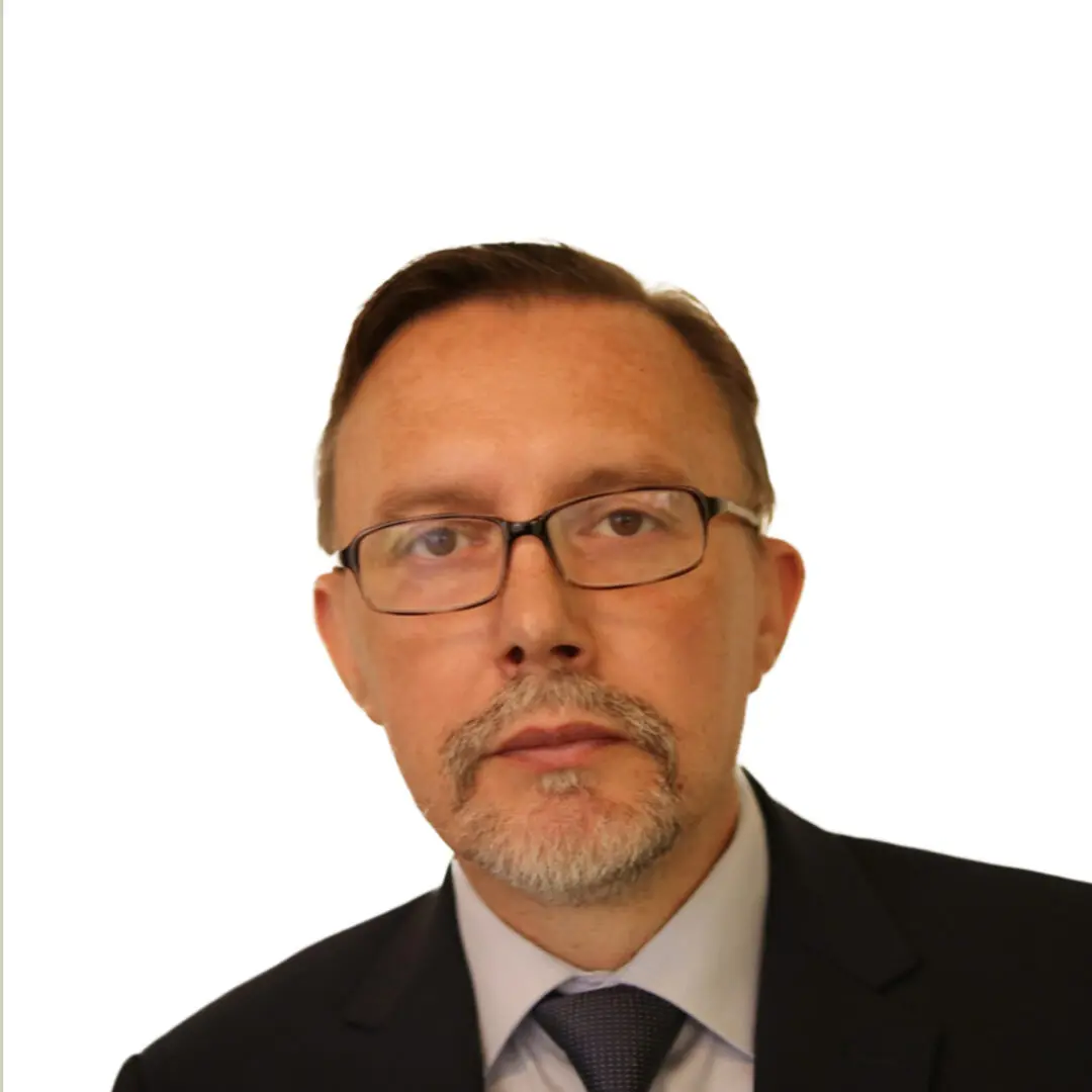 Man in suit with glasses, neutral expression.